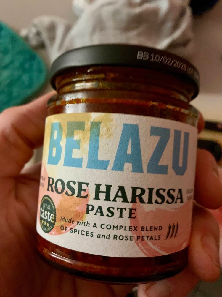 Ein Glas Rosen Harissa der Firma Belazu. Text unter dem Schriftzug Rose Harissa Paste: Made with a complex blend of spices and rose petals.