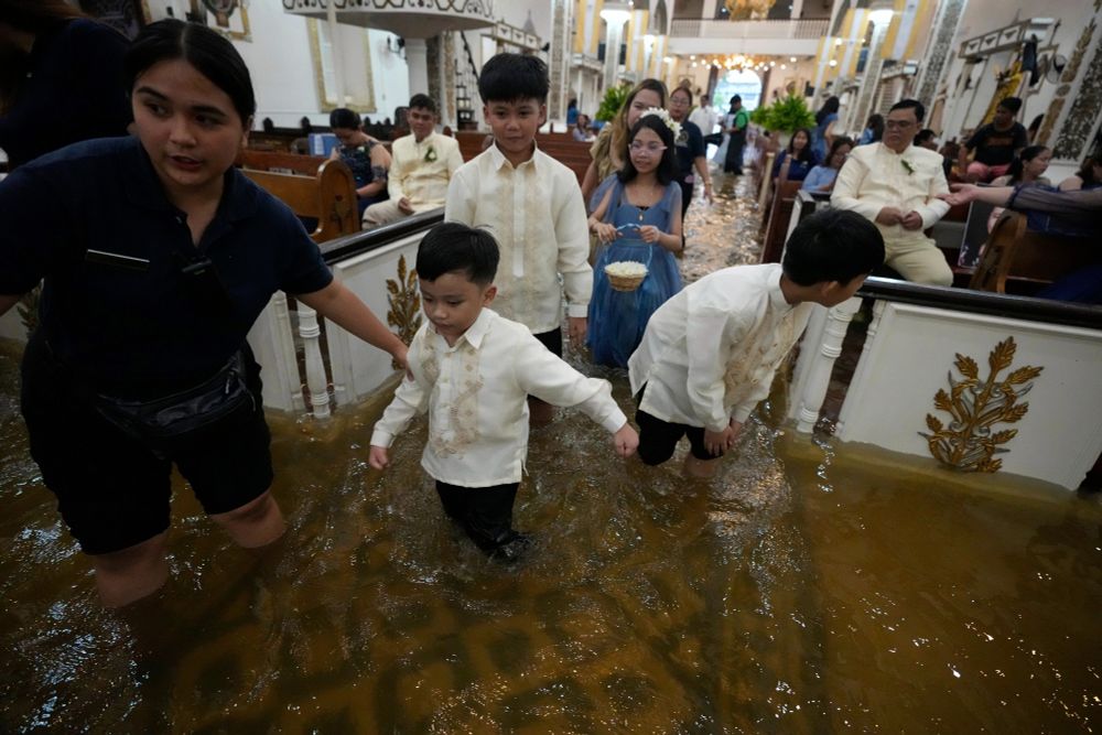 Wedding guests walk inside a flooded church. (Aaron Favila / AP)