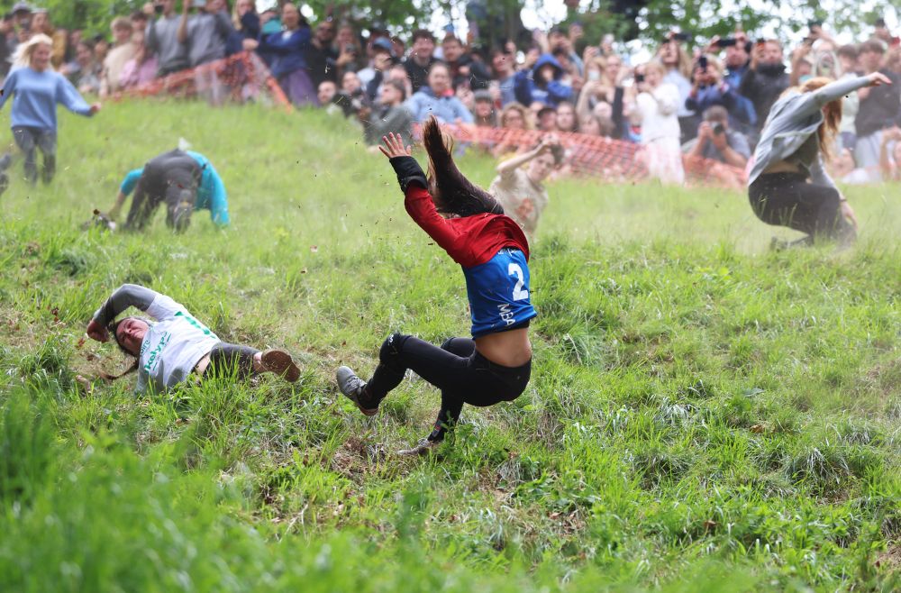 Competitors tumble head over foot during a race down a steep grassy hill. (Cameron Smith / Getty)