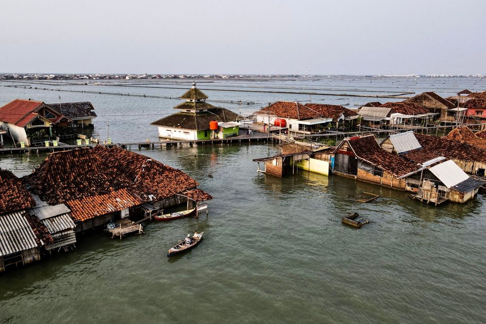 An elevated view of a cluster of houses surrounded by seawater, connected by boardwalks. (Bay Ismoyo / AFP / Getty)