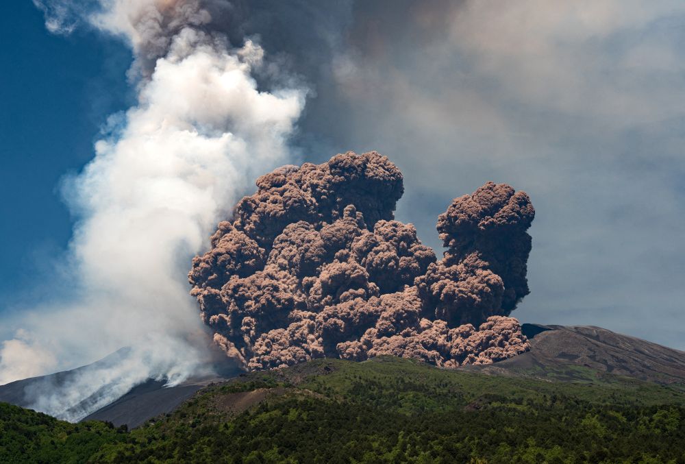 A large plume of brownish-colored ash rises from the top of a volcano. (Marco Restivo / Reuters)