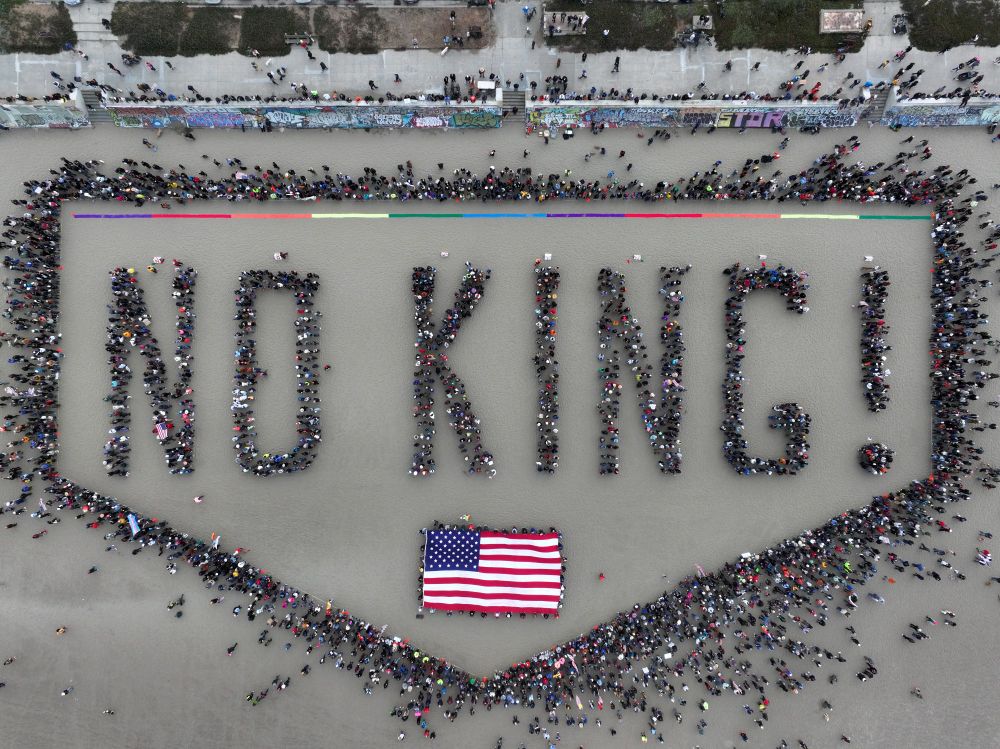 An aerial view of a crowd gathered on a beach in San Francisco, standing in groups, spelling out the words 'No Kings!' (Tayfun Coskun / Anadolu / Getty)