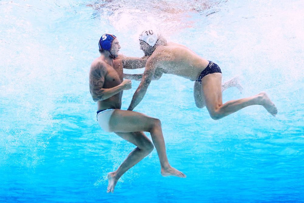 Two water polo players clash underwater, one appears to be grabbing the swimsuit of the other. (Maddie Meyer / Getty)
