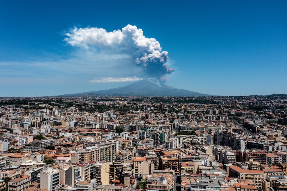 A broad view across city buildings, with an erupting volcano in the background. (Fabrizio Villa / Getty)