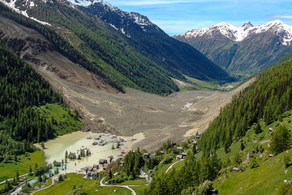 An aerial view of an Alpine valley after a massive landslide, with a cluster of houses being flooded on the uphill side. (Alexandre Agrusti / AFP / Getty)