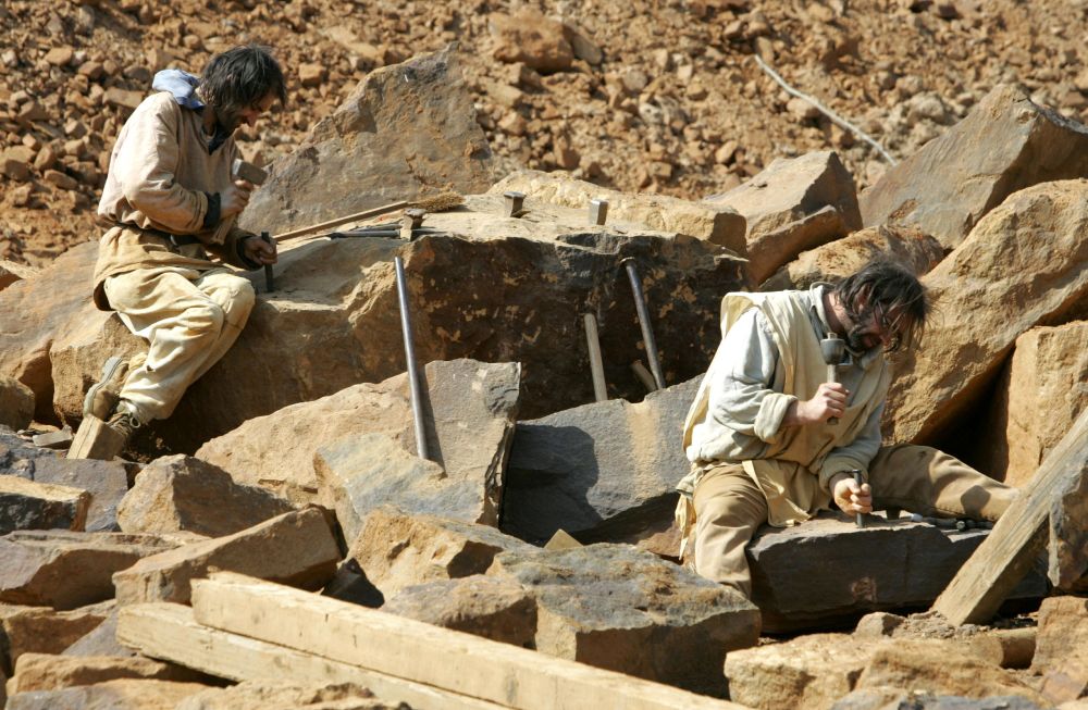 Stonecutters in medieval-style clothing work at a construction site. (Jacky Naegelen / Hans Lucas / Reuters)