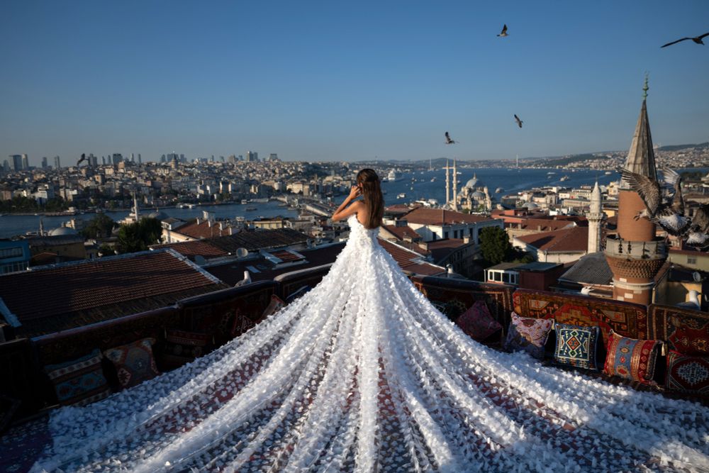 A woman wearing a very long dress stands at the corner of a rooftop overlooking the city of Istanbul. (Ozan Kose / AFP / Getty)
