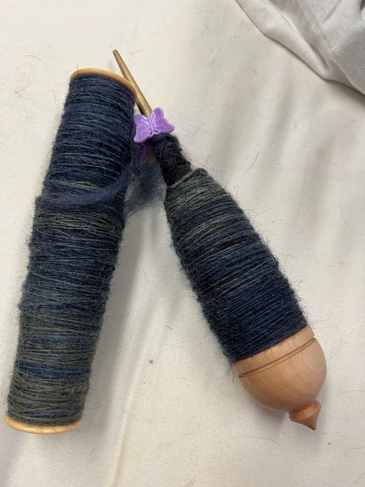 This is a small Kravelli ‘Tibetan’ style supported spindle, filled to capacity with Cheviot. Also a LeClerc bobbin, the kind that goes in a boat shuttle used in weaving. I wind the cop off the spindle onto the bobbin and then fill the spindle again. So far I have three full bobbins and one half full, that will be full when I finish the current cop on the spindle. I’ll ply these into a 4-ply yarn. 