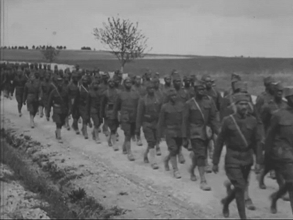 a group of soldiers march down a dirt road