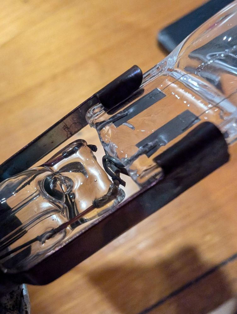 close-up of wires twisted around each other at the junction between a small halogen globe and the innards of an older style light globe. the parts are held together with a copper clip