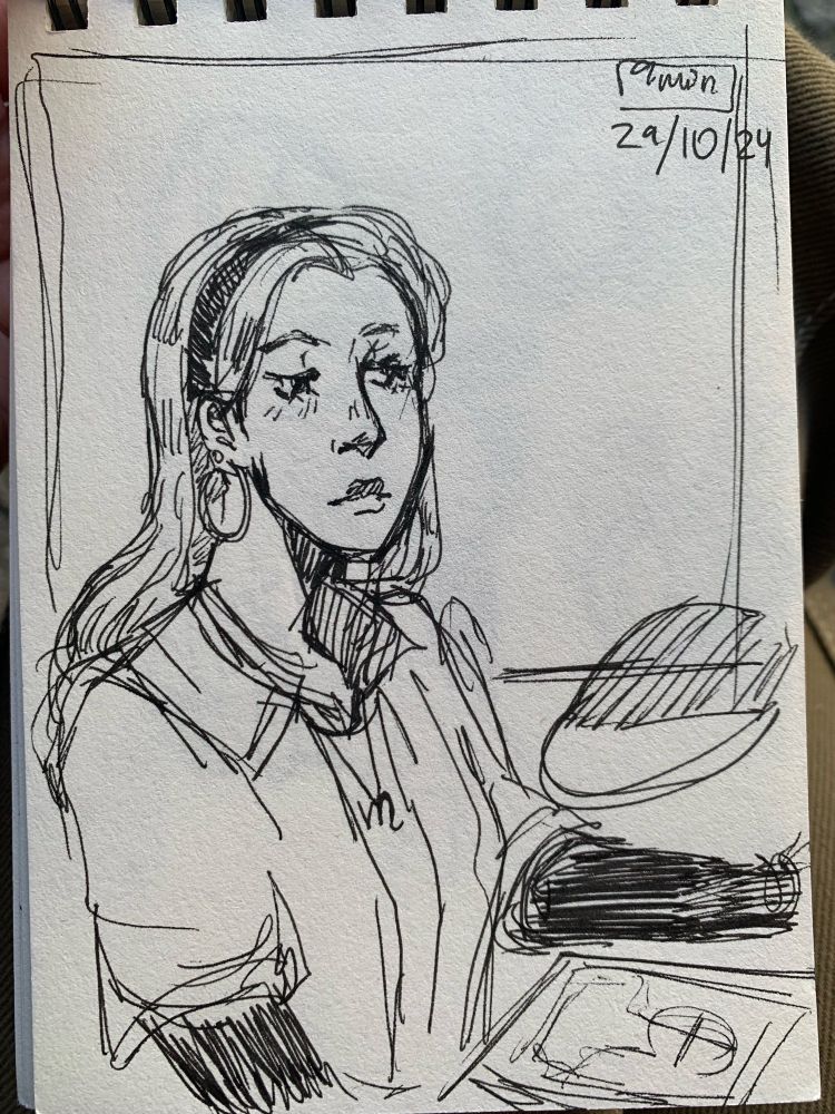 Sketch of a young girl with long hair,  headband and hoop earings, sitting and staring downwards, next to a piece of paper with a sketch on it 