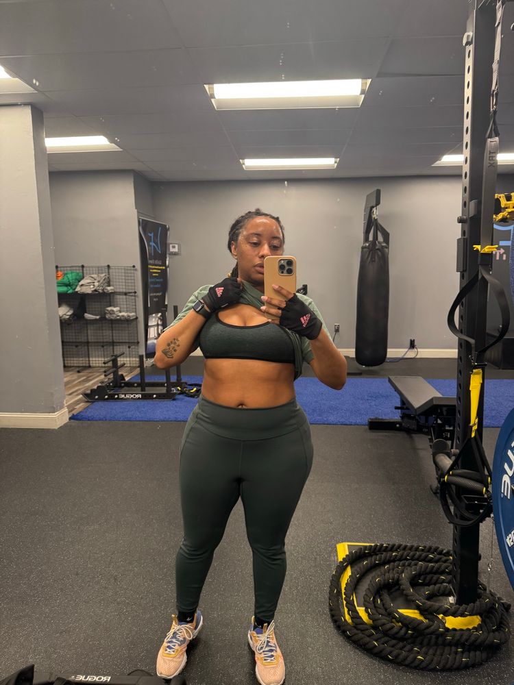 Black fem-ish presenting nonbinary person wearing green in a gym