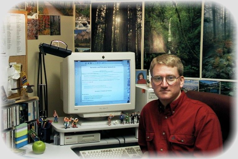 photo of Dan Russell (white male, approximately 30 years old, blond hair and glasses, wearing a red shirt) sitting to the right of a computer monitor.