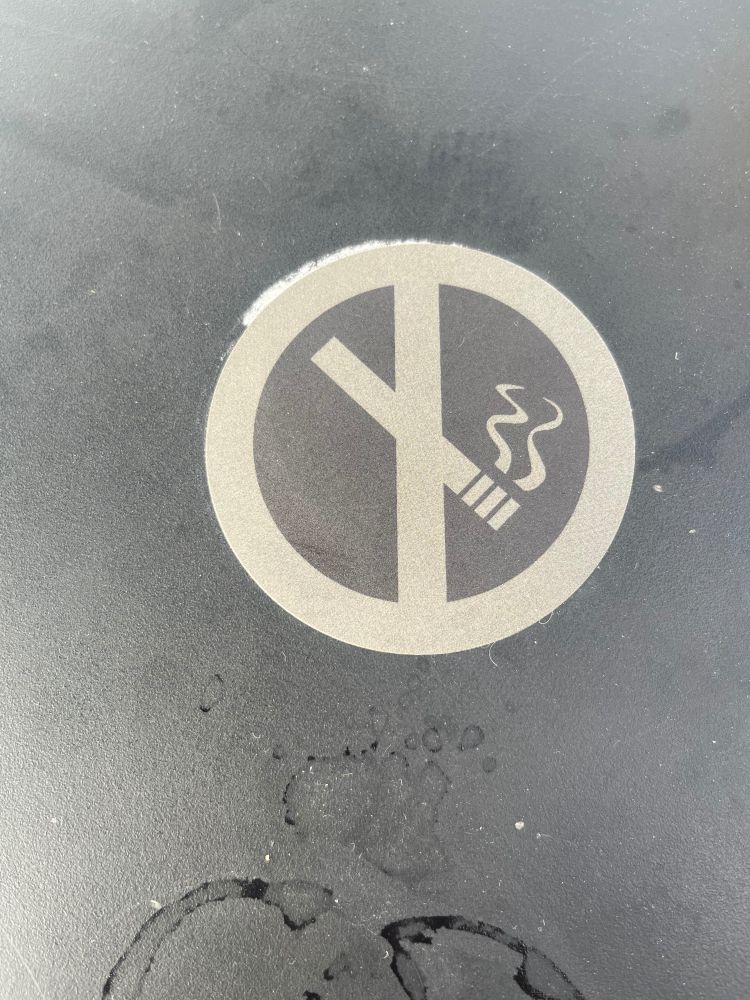 A no smoking sign on a kind of dirty table 