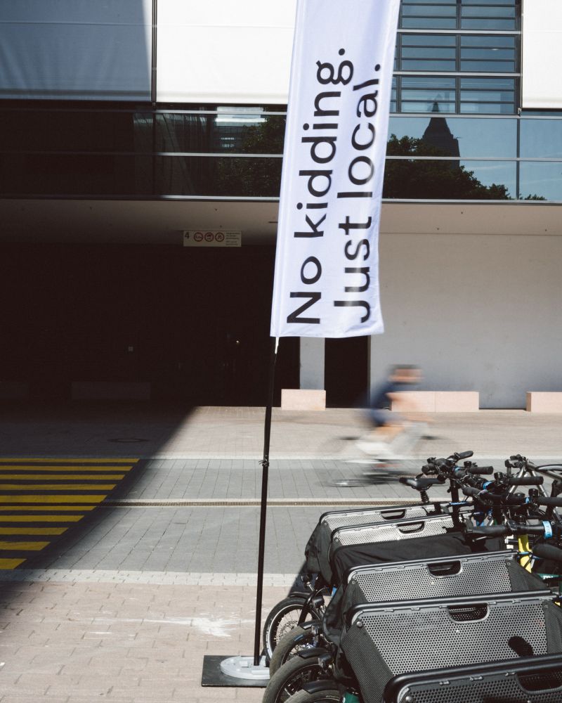 The accessible ALT text in English follows below

Deutsch – Nahaufnahme der muli BOX auf einem lilafarbenen Ausstellungsbike auf der Eurobike. Die Box ist verschlossen und trägt den Aufdruck „muli BOX ~350 liters total volume“. Eine Person geht im Hintergrund vorbei.

English – Close-up of the muli BOX on a purple demo bike at Eurobike. The box is closed and labeled “muli BOX ~350 liters total volume.” A person is walking in the background.