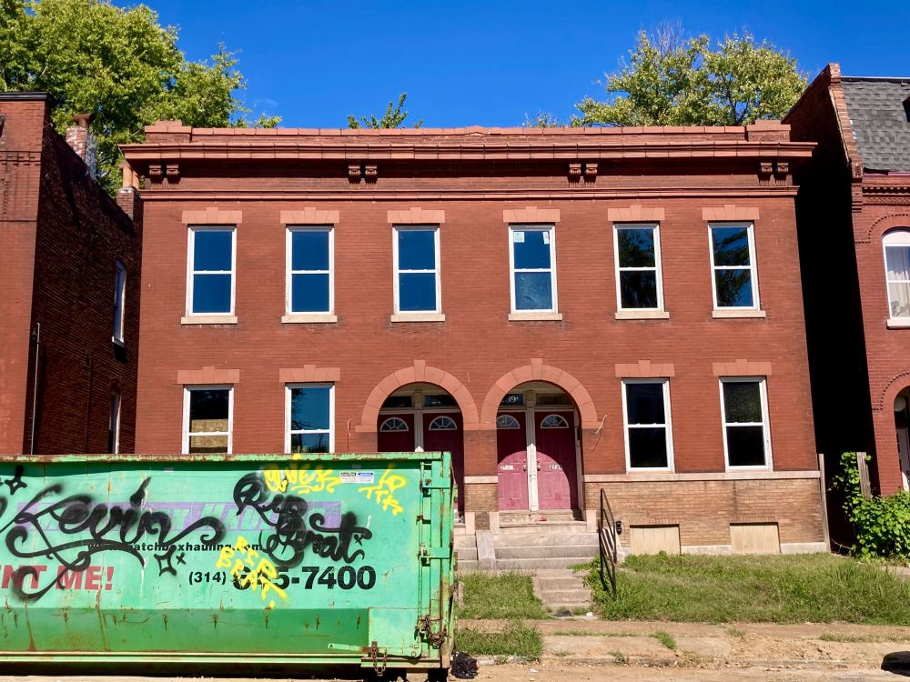 2 story red brick four-fam under renovation to on with a dumpster in front. 