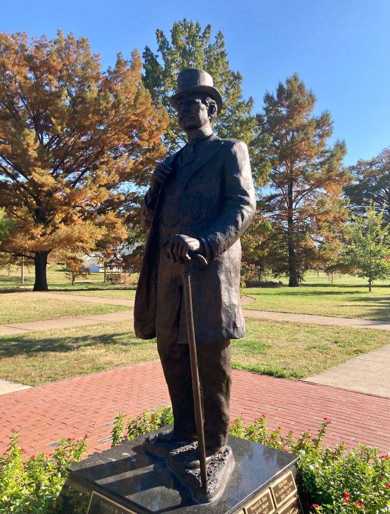A statue of a man standing and with his facial features obscured in shadow. 