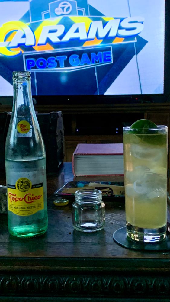 A bourbon rickey with topo chico and a shot glass beside