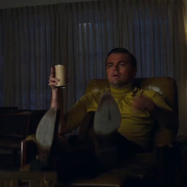 a man in a yellow shirt is sitting in a chair holding a cup and pointing