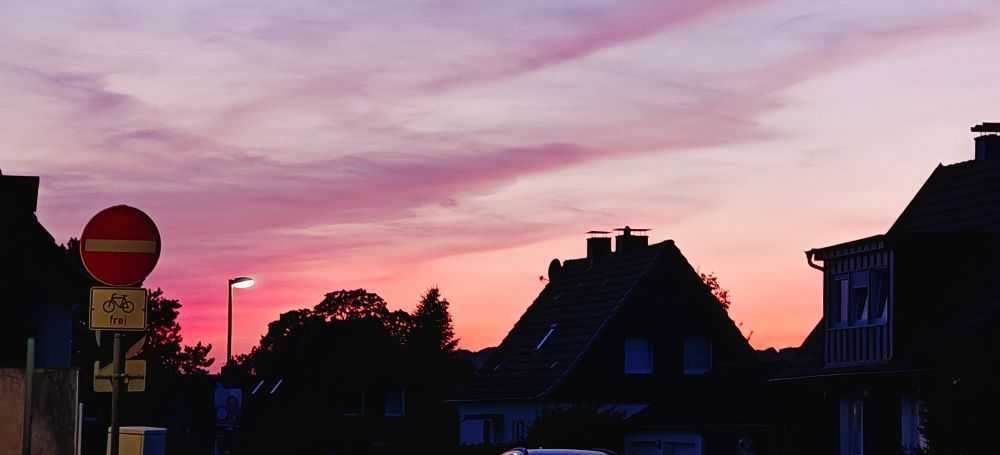 Abendrot am Himmel über det Silhouette vom Häusern, die Farben reichen von Lachs über pink und Flieder bis zu lila