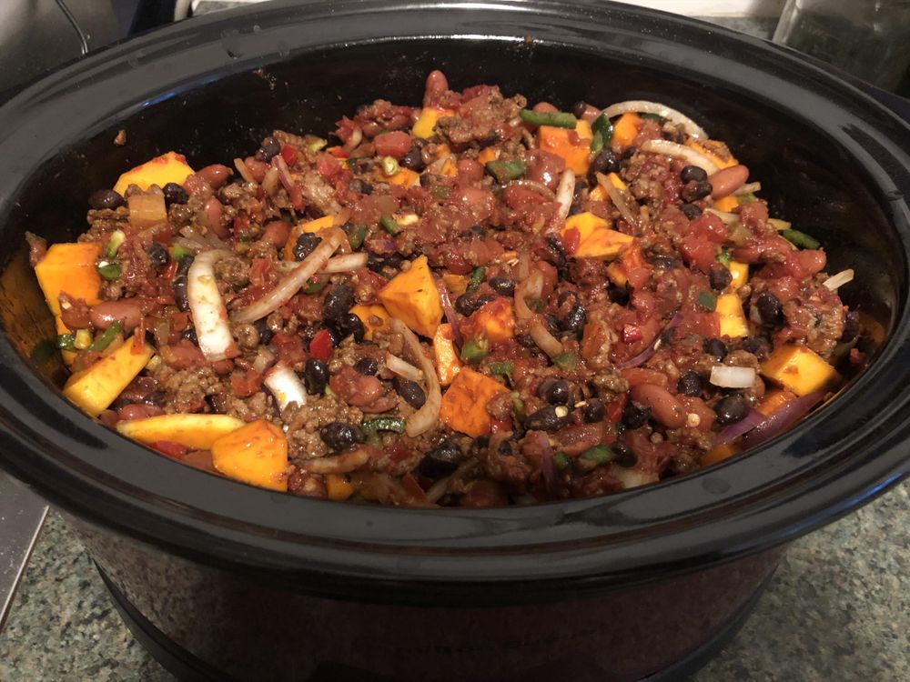 Slow cooker filled with chili waiting to be cooked.