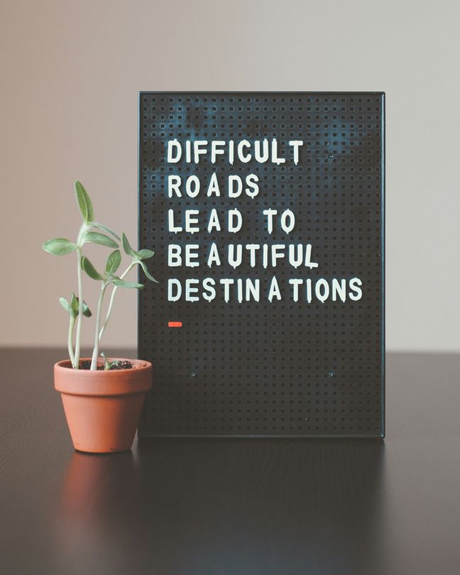 White letters are pinned against a black board. Text reads: Difficult roads lead to beautiful destinations.