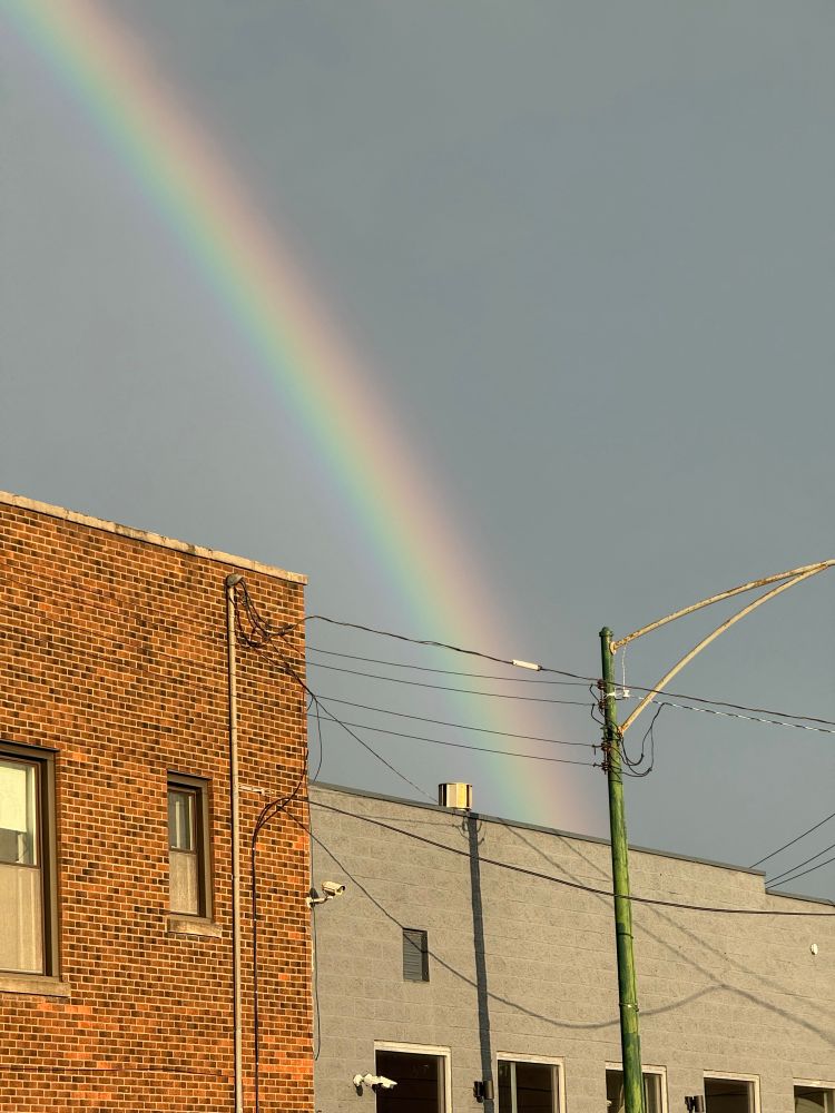 A rainbow appears to beam directly through the roof of a building.