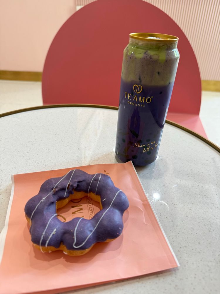 An ube mochi donut and a ube matcha boba tea shown on a cafe table.