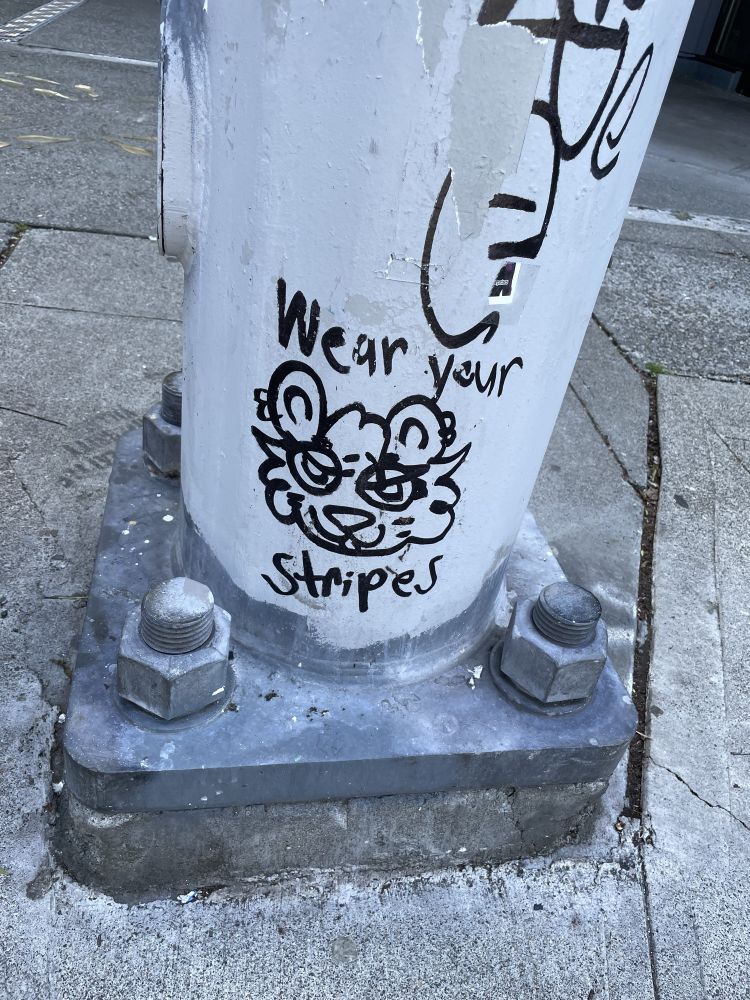 Graffiti of a creature with the text “wear your stripes”