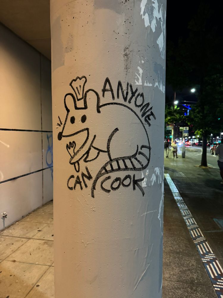 Graffiti of a rat chef holding a fork with the text “anyone can cook”