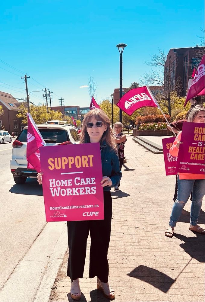 Christine Saulnier and other CUPE delegates with Support Home Care Workers signs and CUPE NS flags in Sydney NS