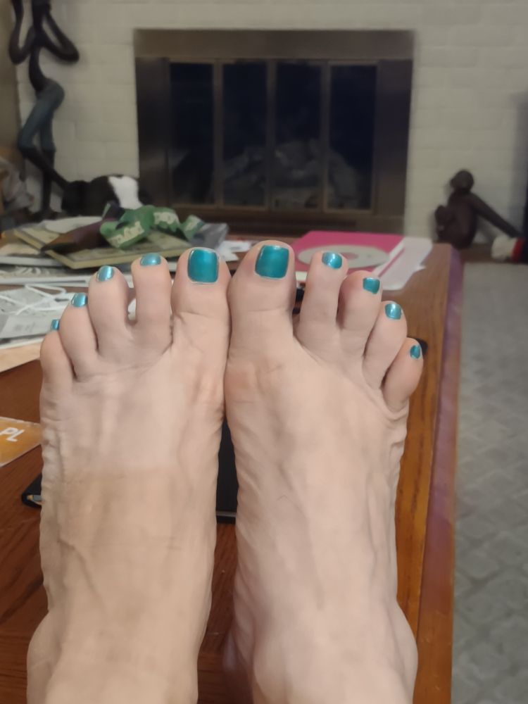 Two feet with toenails painted teal.