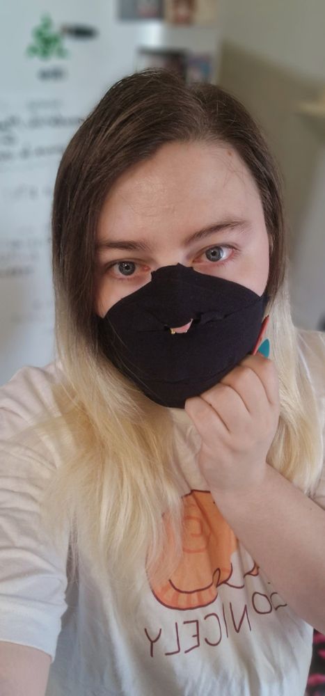 Me, gagged with Sport tape, looking at the camera, wearing a long white shirt with with an orange cat drawn on it, with "So Nicely" written under the cat.