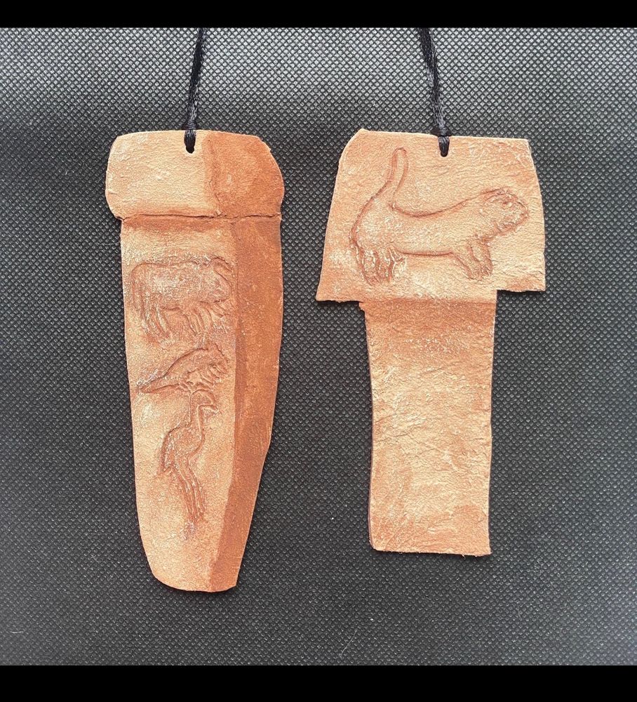 Pair of pillar shaped tan ornaments with animal figures