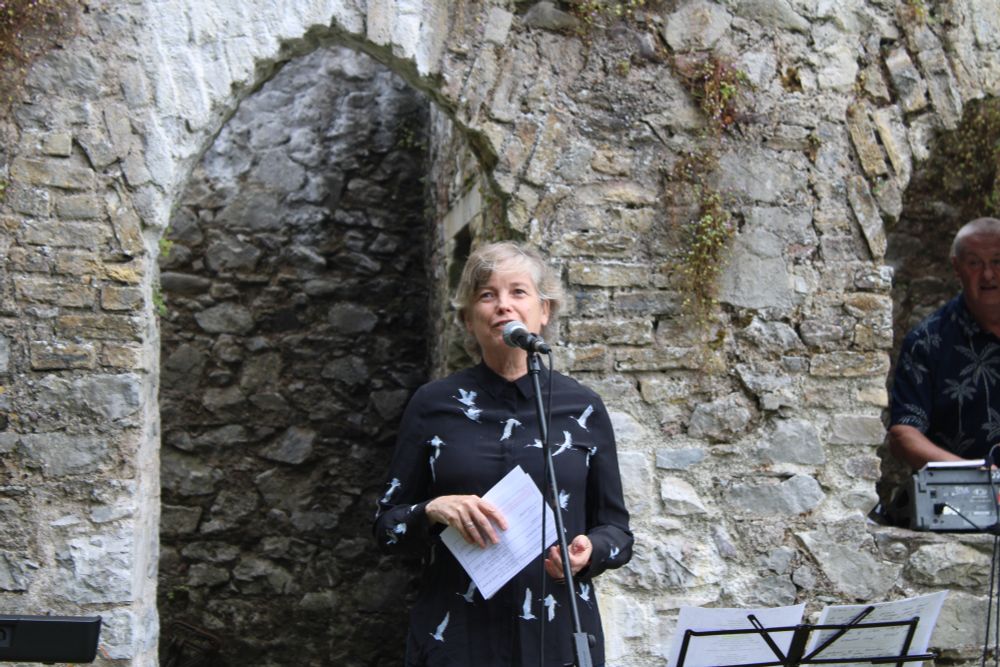 A woman looking out at the crowd speaking into a microphone.