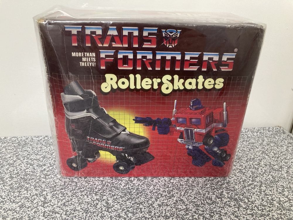 Transformers Roller Skates! A box using the typical G1 Autobot red grid & sunburst packing design with a picture of the black skates (with Tranformers Logo) and Optimus Prime box art