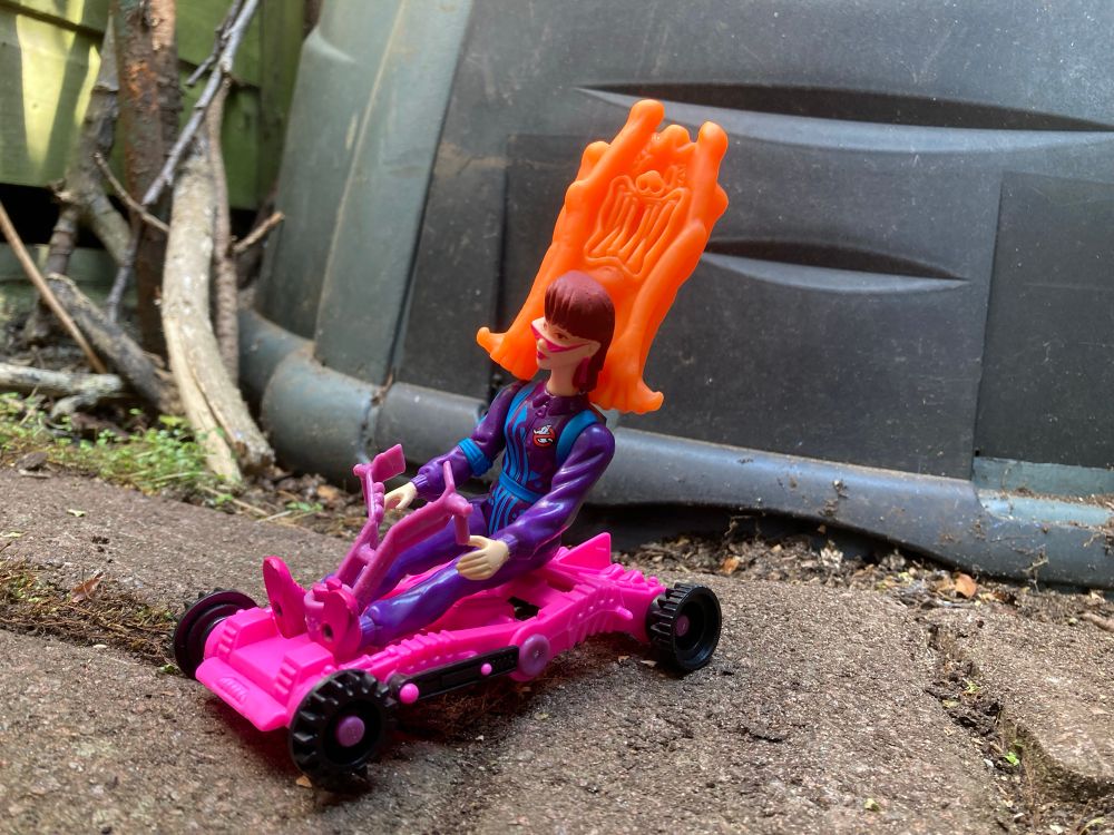 Janine rides her cart with Stetch grabbing on for dear… death