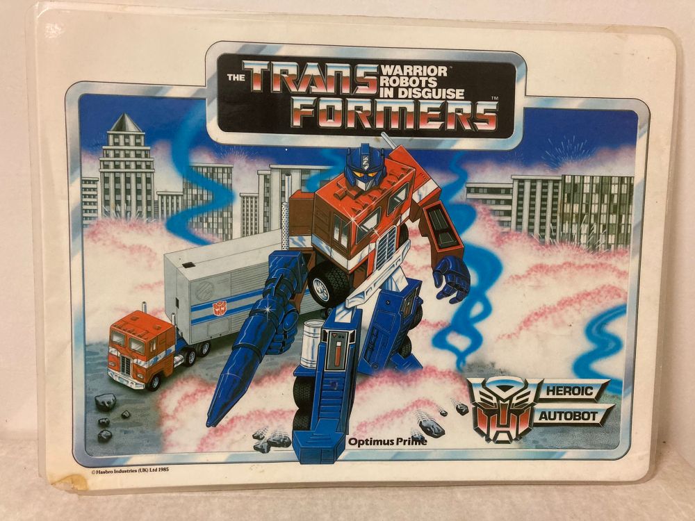Transformers table mat from Icarus - Optimus Prime poses in front of himself amidst a pile of steaming pink-tinged foam. Must have been a hell of a party!