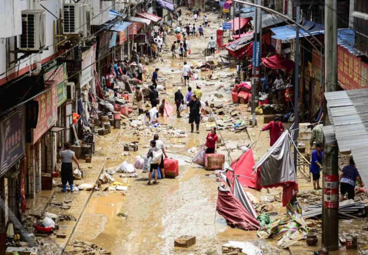 People walk with their belongings at a flood-affected area in Congjiang, in southwestern China's Guizhou province [China Out/AFP via Al Jazeera]