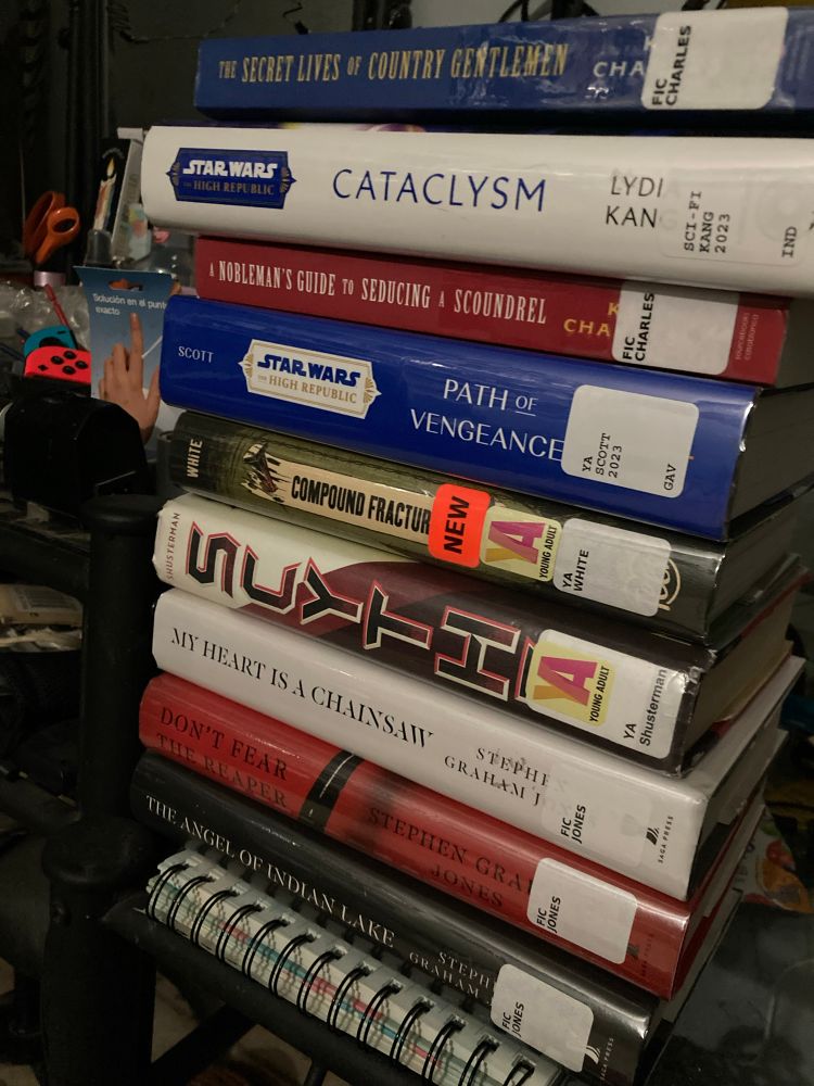 Stack of books. From the top down 
The Secret Lives of Country Gentlemen by KJ Charles
Cataclysm by Lydia Kang
A Nobleman’s Guide to Seducing a Scoundrel by KJ Charles
Path of Vengeance by Kavan Scott
Compound Fracture by Andrew Joseph White
Scythe by Neal Shusterman
My Heart Is A Chainsaw by Stephen Graham Jones
Don’t Fear The Reaper by Stephen Graham Jones
The Angel Od Indian Lake by Stephen Graham Jones 