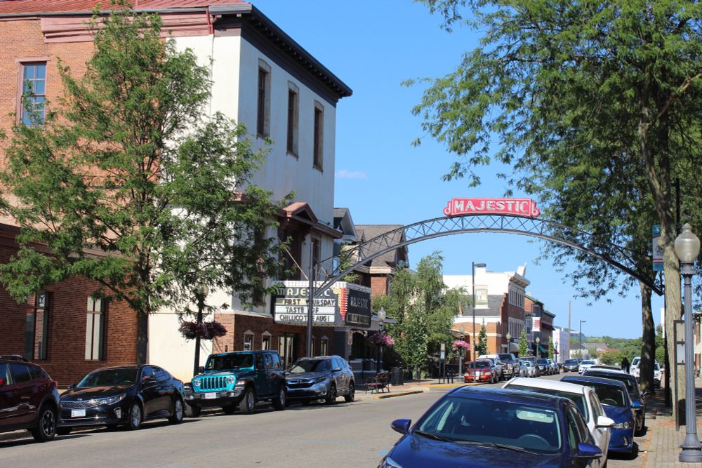A red brick building with white front has a marquee reading Majestic. A Metal arch runs over the street with Majestic above it.