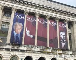 Image of Donald Trump's large banner at the USDA building.
To the Lincoln banner on the right, three more have been added so that Lincoln's hand is flipping Trump off.
