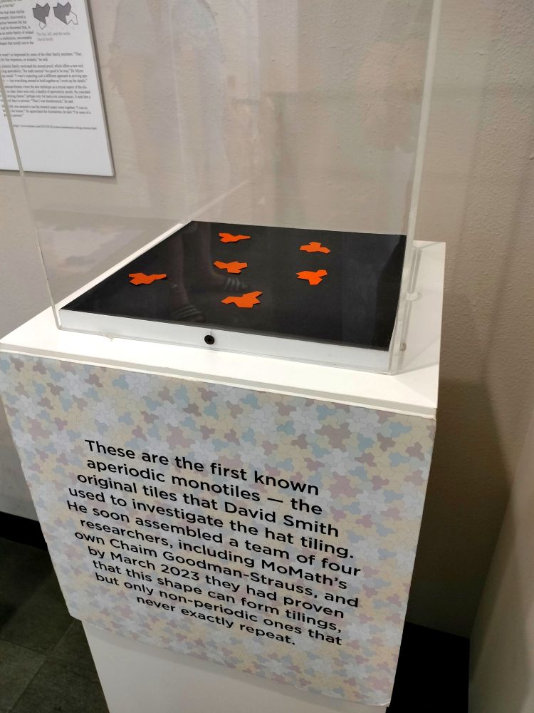 A display case containing cutouts in the shape of the hat monotile