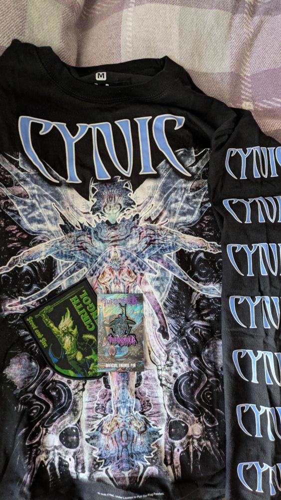 A long sleeved top with the art of Cynic's Traced in air on and the band logo down the sleeve, a patch for the band Cirith Ungol and an enamel pin for the band Tomb Mold 