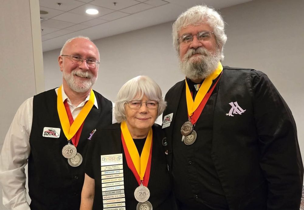 Me, a slightly shorter woman, and my slightly taller husband, all standing side by side dressed in our club's final uniform of dress shirts & vests. Each of us is wearing our original 10 year medallion, as well as our new 20 year medallions.