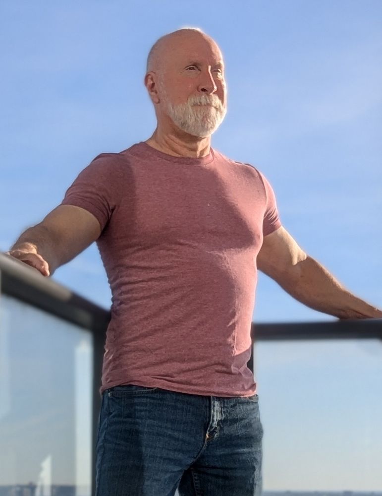 Old guy in jeans and a red t-shirt, standing on a hotel balcony, staring heroically into the distance because he doesn't have his glasses and can't see a damn thing.