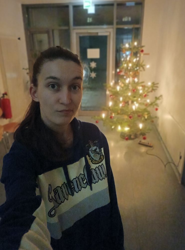 Eine skeptisch guckende Fraupfoetchen mit dem hübsch beleuchteten Labor-Weihnachtsbaum im Hintergrund.