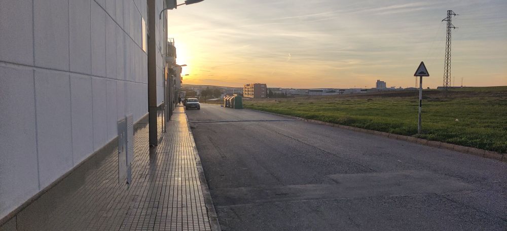 A photo of the road at sunset with a field at the side