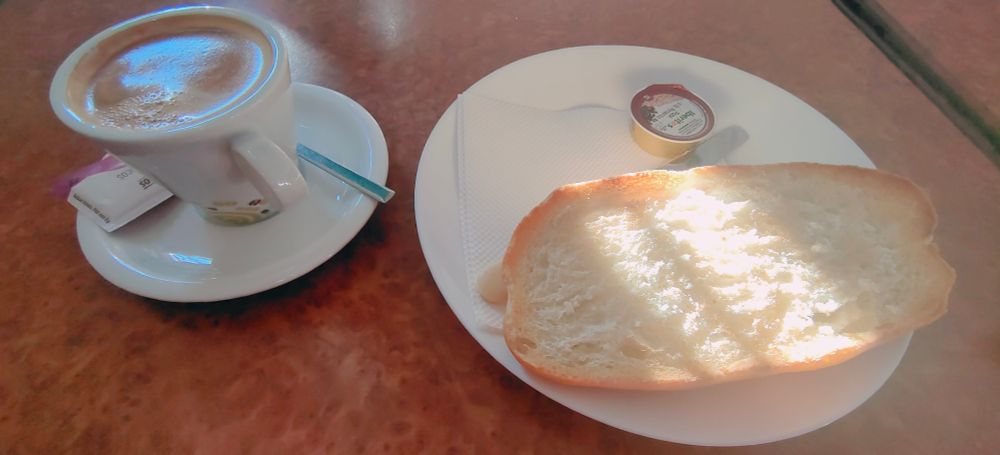 A photo of a cup of coffee and a toast.