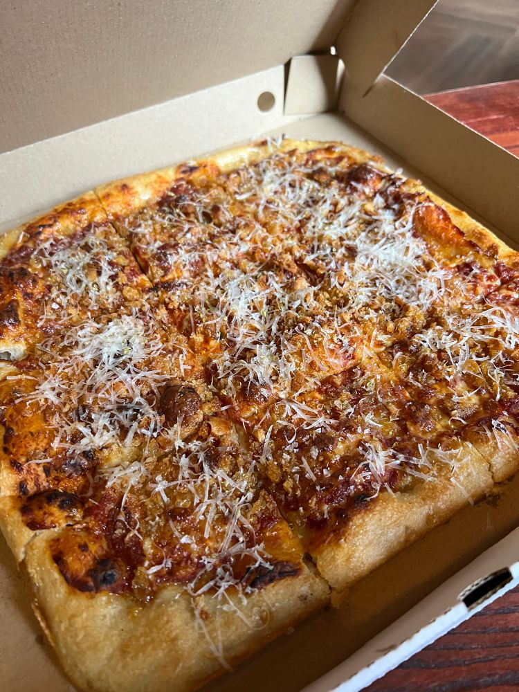 A Sicilian-style pizza with added cheese, cut into 9 slices in a pizza box